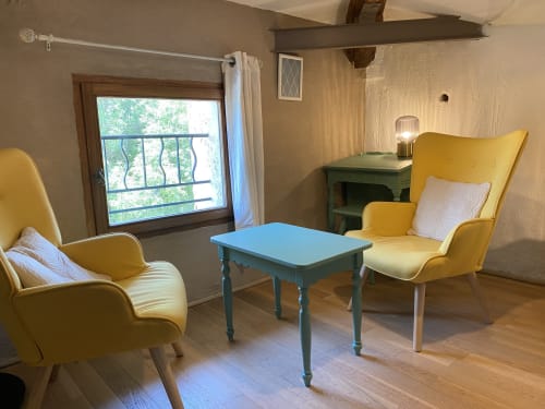 Chambre Les Vignes au Mas de la Soie avec fauteuils jaunes, table bleue et vue sur le jardin