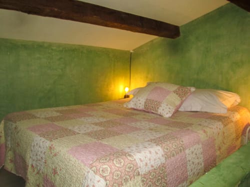 Camera accogliente al Clos B&B di Saint-Cyr sur Mer con pareti verdi, biancheria patchwork e travi in legno a vista