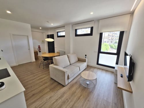 Apartamento BR SILGAR en Sanxenxo con sofá beige, mesa de comedor, suelos de madera y mobiliario moderno