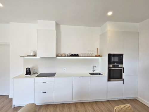 Cocina moderna blanca en apartamento BR SILGAR, Sanxenxo con electrodomésticos de acero inoxidable y piso de madera
