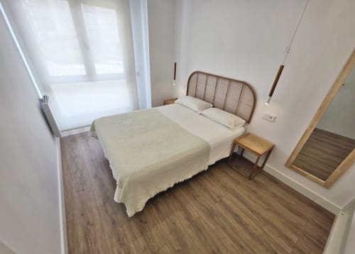 Dormitorio luminoso en apartamento BR Silgar, Sanxenxo con cama doble, mesita de noche de madera y pisos de parqué