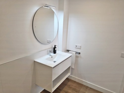 Baño moderno con tocador y espejo redondo en el apartamento BR SILGAR de Sanxenxo, España
