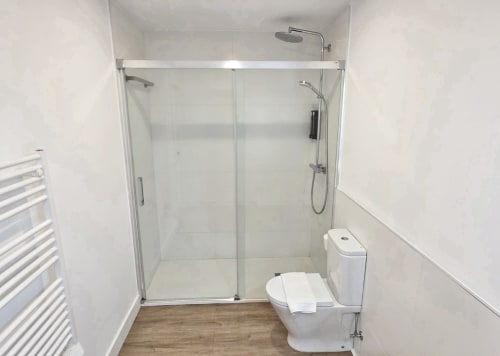 Baño moderno en apartamento BR SILGAR Sanxenxo con ducha de cristal, inodoro blanco, toallero calefactable y madera