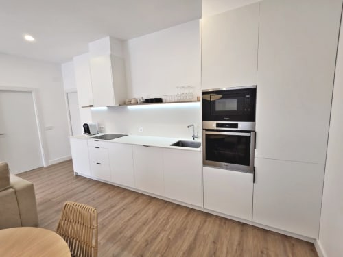 Moderna cocina blanca en apartamento BR SILGAR, Sanxenxo con electrodomésticos integrados y suelos de madera