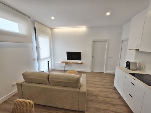 Apartamento moderno en BR Silgar de Sanxenxo con sofá beige, cocina, televisor y salón luminoso