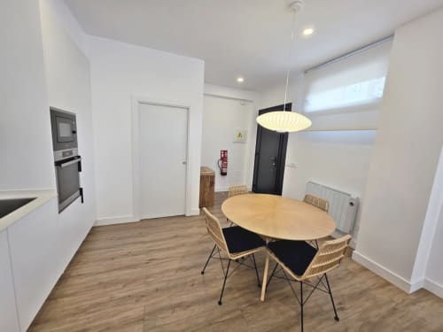 Área de cocina-comedor moderna en apartamento BR SILGAR, Sanxenxo, con mesa de madera, sillas contemporáneas y acero inoxidable
