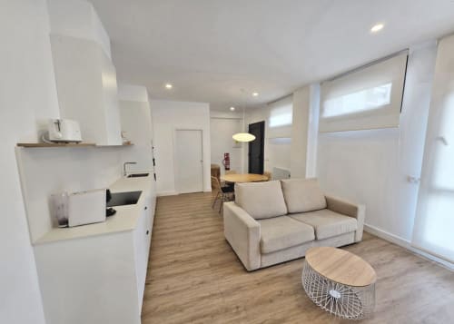 Apartamento moderno en Sanxenxo con salón, cocina americana, sofá beige, muebles de madera y luz natural
