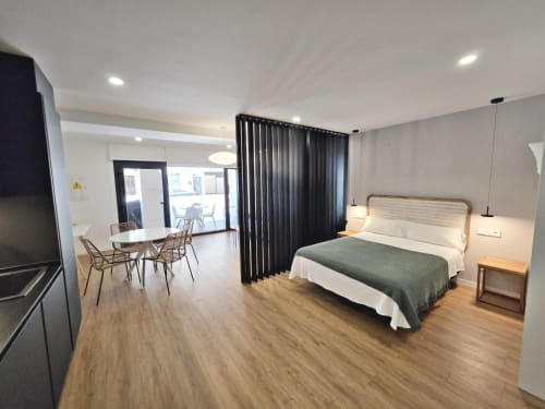 Habitación Club BR Silgar en Sanxenxo con cama, sala de estar, TV y cortina negra divisoria