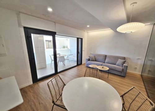 Moderno salón del BR Silgar Club en Sanxenxo con comedor, sofá gris y acceso a balcón