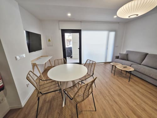 Sala de estar BR Silgar Club en Sanxenxo con mesa redonda, sillas tejidas, sofá, TV y amenidades modernas