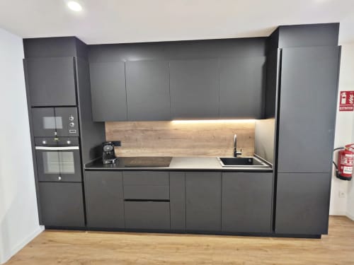 Cocina moderna negra con salpicadero de madera, fregadero y placa de cocción en habitación BR Silgar Club 1, hotel Sanxenxo