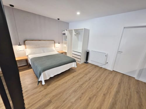 Espacioso dormitorio moderno en BR Silgar Club de Sanxenxo con cama, armario, suelo de madera y paredes blancas