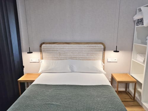 Dormitorio del Club BR Silgar en Sanxenxo con cabecero de rattán, ropa de cama blanca, mesillas de madera y lámparas colgantes