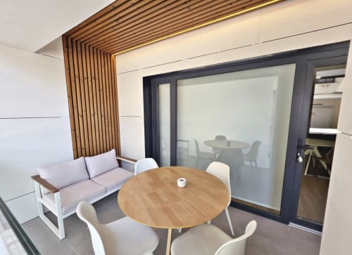 Salón Club BR Silgar en Sanxenxo con mesa redonda de madera, sillas blancas, zona de sofás y modernas puertas de cristal