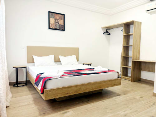 Dormitorio moderno en apartamento de Dakar con cama de madera, almohadas blancas, manta roja y armarios empotrados