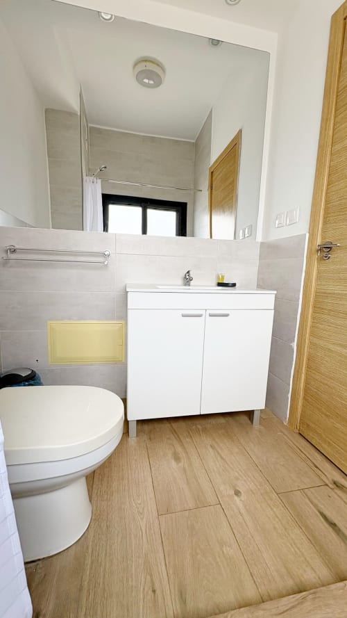 Cuarto de baño moderno del apartamento DBD901 en DakarByDays, Dakar, con lavabo blanco, inodoro y piso con aspecto de madera