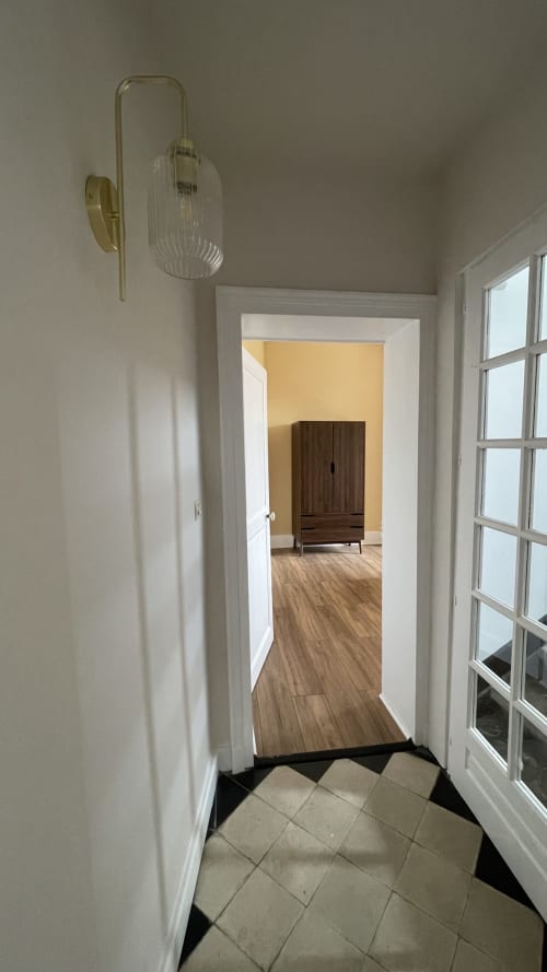 Couloir contemporain du cottage Maison Agami à Rosières aux Salines, parquet bois et applique murale en laiton élégante