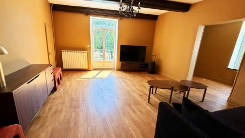 Spacieux séjour du gîte Maison Agami aux murs orange, parquet en bois, TV écran plat et portes-fenêtres donnant sur