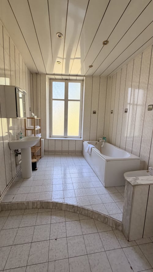 Salle de bain spacieuse de la villa Maison Agami à Rosières aux salines avec baignoire, lavabo et vue sur fenêtre