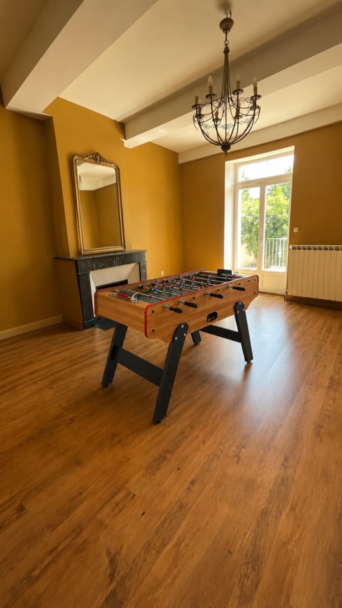 Table de baby-foot dans la salle de jeux élégante aux murs dorés et lustre de la villa Maison Agami