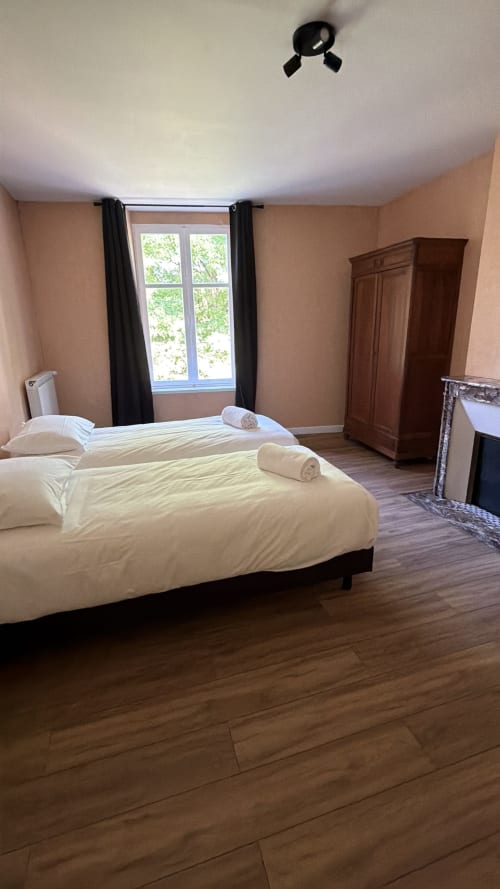 Chambre spacieuse du gîte Maison Agami avec deux lits, parquet, grande fenêtre et penderie à Rosières aux salines