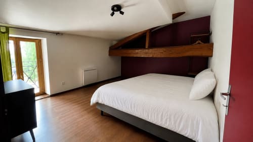 Spacieuse chambre mansardée à la Maison Agami avec lit queen-size, poutres en bois, vue sur jardin et équipements modernes à Rosières aux