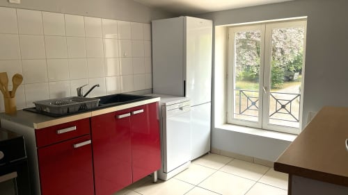 Cuisine moderne aux armoires rouges à l'appartement Maison Agami à Rosières aux salines, portes avec vue sur le jardin