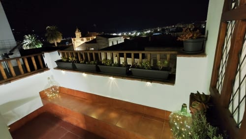 Terraza Mirador Medieval iluminada de noche con macetas decoradas, vistas de la ciudad y arquitectura histórica de Cáceres