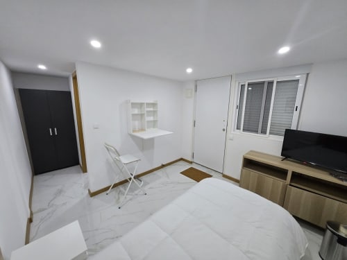 Quarto moderno no Alojamento Boeing AL em Moreirada Maia com cama, TV, escrivaninha, guarda-roupa e portas de vidro deslizantes