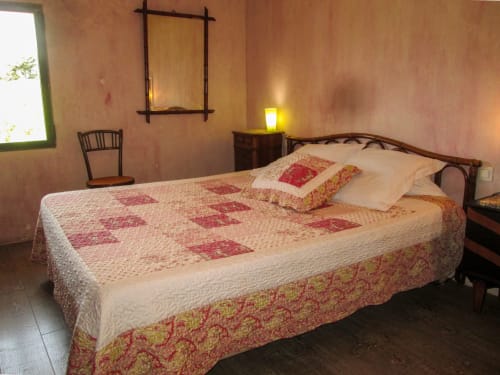 Bedroom at Clos B&B in Saint-Cyr sur Mer with patterned quilt, wooden bed frame, and warm lighting