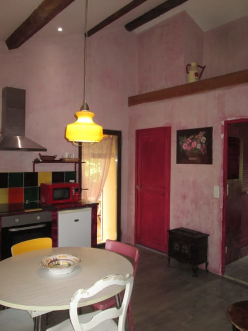 Charming kitchen-dining area at Clos B&B in Saint-Cyr sur Mer with pink walls, yellow pendant light, and retro decor