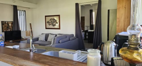 Intérieur moderne et ouvert du gîte Habitation Villa Les Cassias avec cuisine, canapé gris, télévision et chambre.
