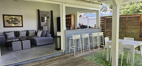 Salon moderne avec bar, canapé gris, accès patio à Villa Les Cassias, Guadeloupe
