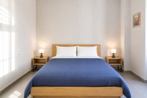 Camera moderna a Darna Rooms Napoli con letto matrimoniale, comodini in legno, biancheria blu e luminosa luce naturale