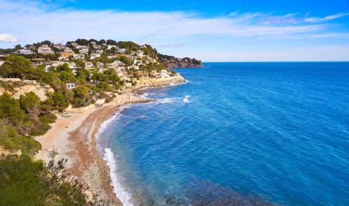 Villa costera Casa Marina Suites con playa mediterránea, mar turquesa y viviendas en ladera en España