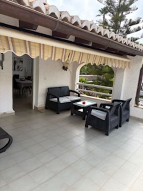 Patio de Casa Marina Suites con asientos negros, toldo rayado y vistas al mar en España