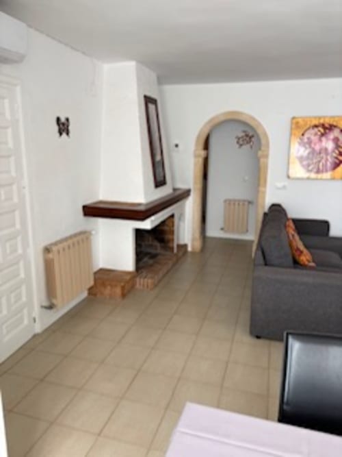 Amplia sala de estar en suite de Casa Marina Suites con chimenea, puerta con arco, sofá gris y piso de cerámica