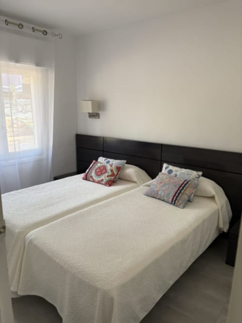 Dormitorio moderno con camas gemelas, cabecero negro, ropa de cama blanca y almohadas decorativas en Casa Marina Suites, España