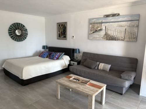 Suite moderna en Casa Marina Suites con cama, sofá gris, mesa de madera, arte mural y reloj decorativo
