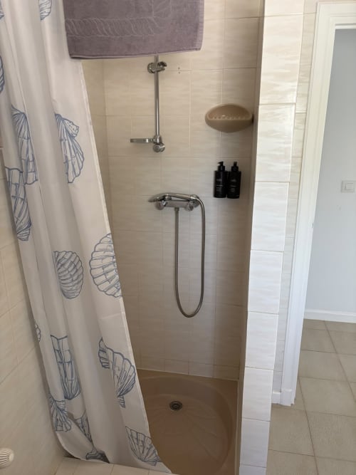 Moderno baño con ducha con vistas al mar en Casa Marina Suites, con paredes de azulejos, alcachofa de lluvia y detalles con patrones de conchas