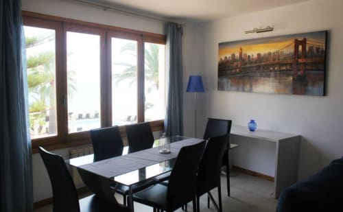 Comedor de la Suite 6 de Casa Marina Suites con ventanales con vistas al mar, sillas negras, obras de arte y lámpara azul