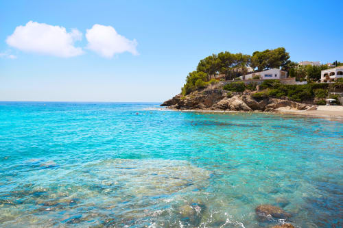Plage méditerranéenne turquoise avec crique rocheuse, villas blanches et pins aux Casa Marina Suites, Espagne