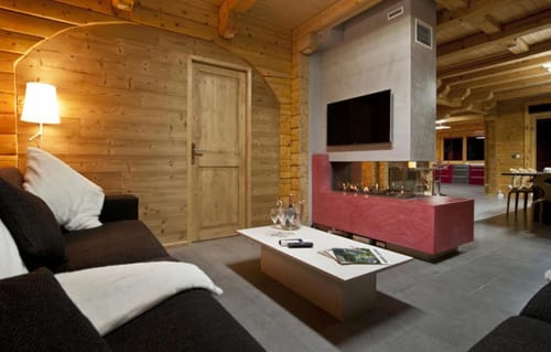 Séjour de chalet moderne aux Chalets d'Aline avec mobilier noir, foyer et vue sur les montagnes