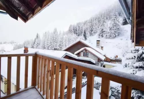 Balcon enneigé des Chalets d'Aline avec vue sur la forêt de montagne à La Plagne Tarentaise