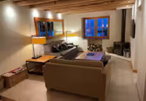 Salon moderne de la villa Les Chalets d'Aline avec vue montagne, télévision écran plat, sièges beiges et touches orangées