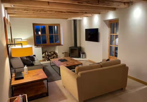 Séjour moderne de la villa Les Chalets d'Aline à La Plagne avec sièges confortables, cheminée et vue sur les montagnes