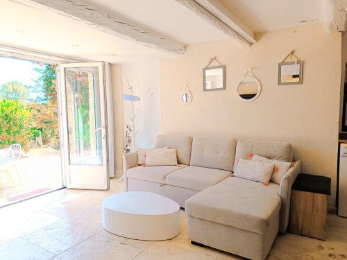 Séjour lumineux à la gîte Les Mûriers D'Engaspaty à Seillans avec canapé beige, table basse blanche et vue sur le jardin