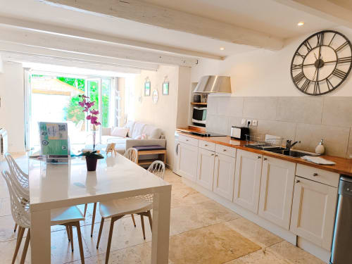 Cuisine-salle à manger spacieuse et lumineuse au gîte Les Mûriers D'Engaspaty à Seillans, avec meubles blancs et plan de travail en bois