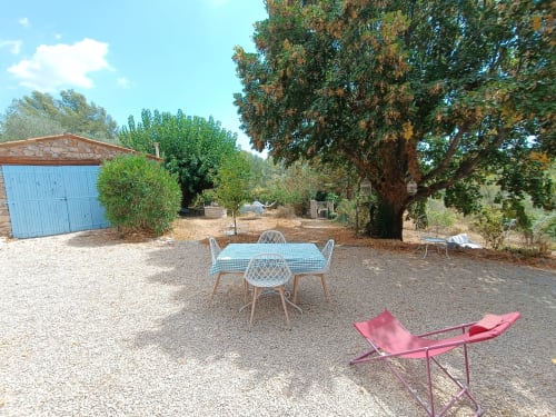Cour rustique du gîte Les Mûriers D'Engaspaty à Seillans avec mobilier extérieur, arbres et bâtiments en pierre