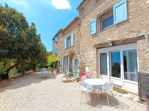 Charmante cour de gîte en pierre à Seillans avec volets bleus, mobilier extérieur et jardins méditerranéens